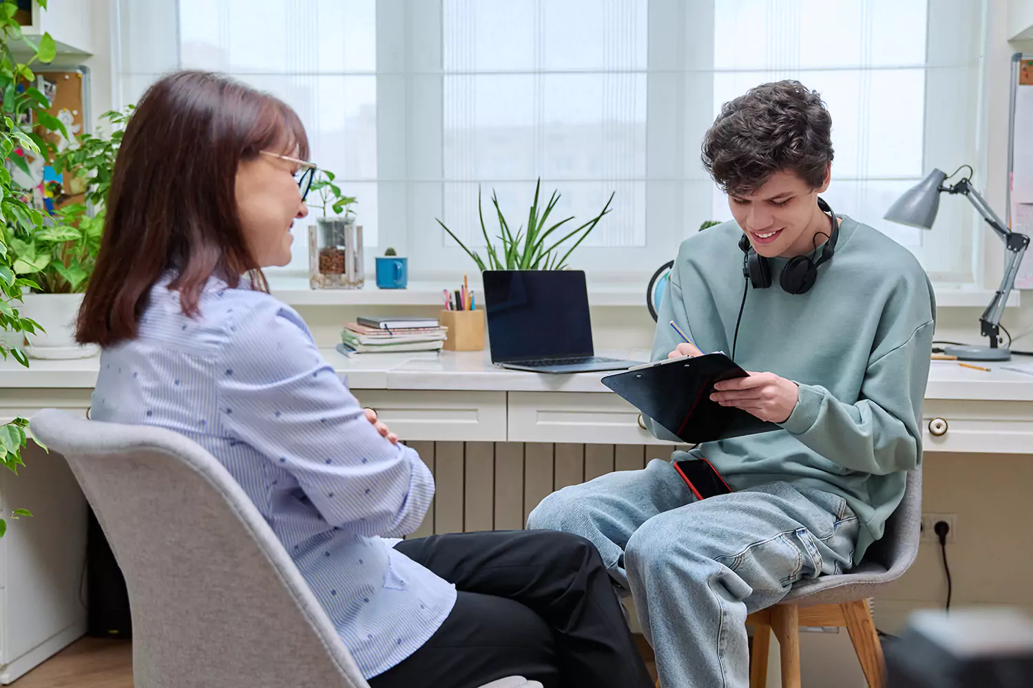 Teenage boy filling out clipboard while talking to support worker